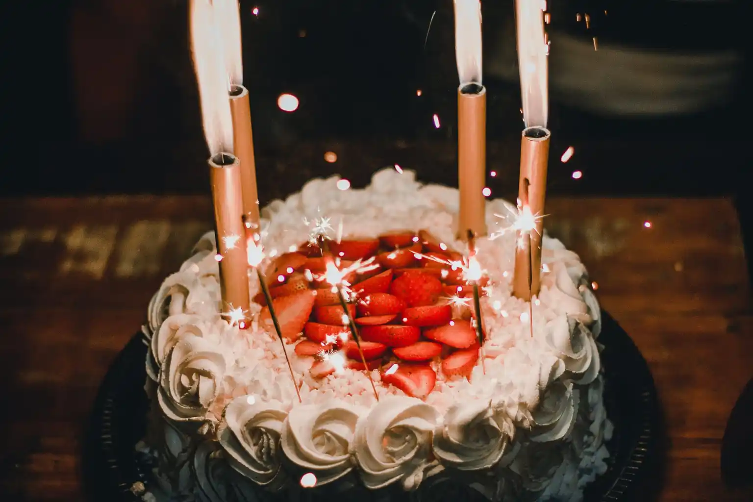 Cake with strawberry toppings and sparklers as candles