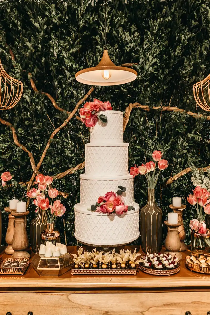 Four-layered wedding cake amidst a spread of dessert